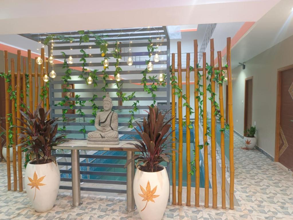 KottakupamParadise Breeze Inn的一间设有植物桌子和雕像的房间