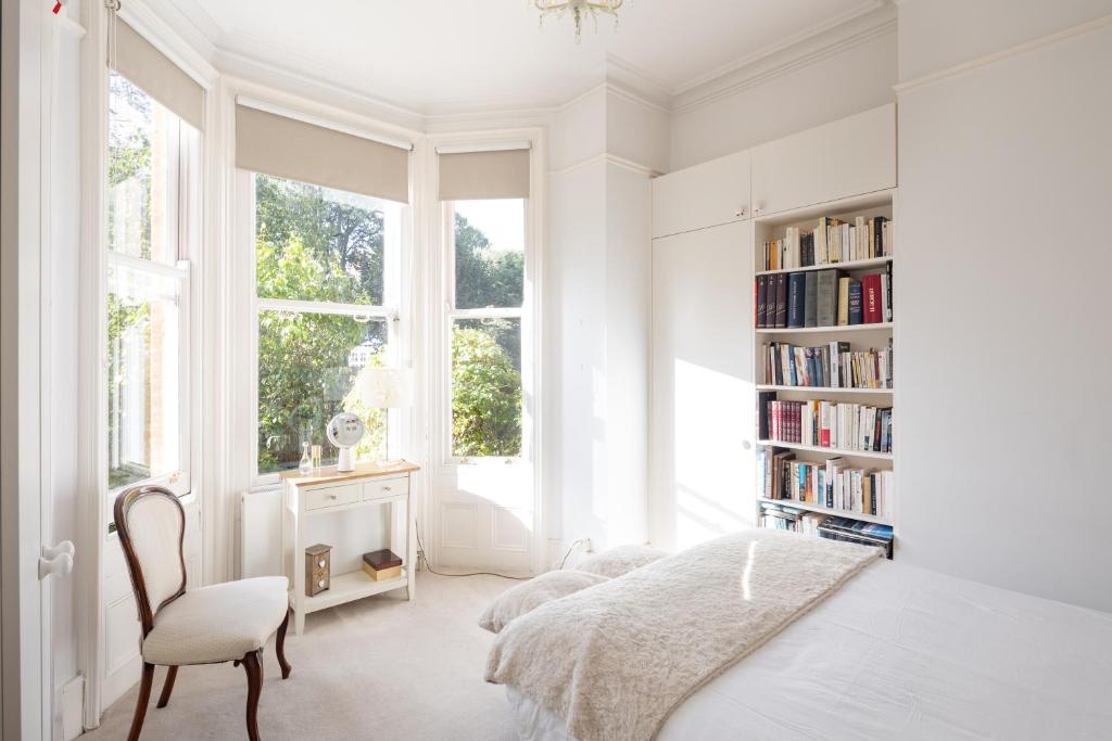 伦敦Veeve - Courtside Charms的一间白色卧室,配有床和书架