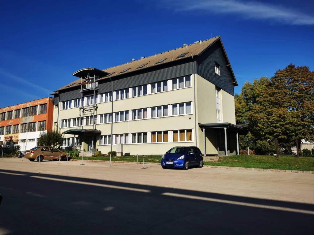多瑙新城Híd Ifjúsági Szálló的停在大楼前的蓝色汽车