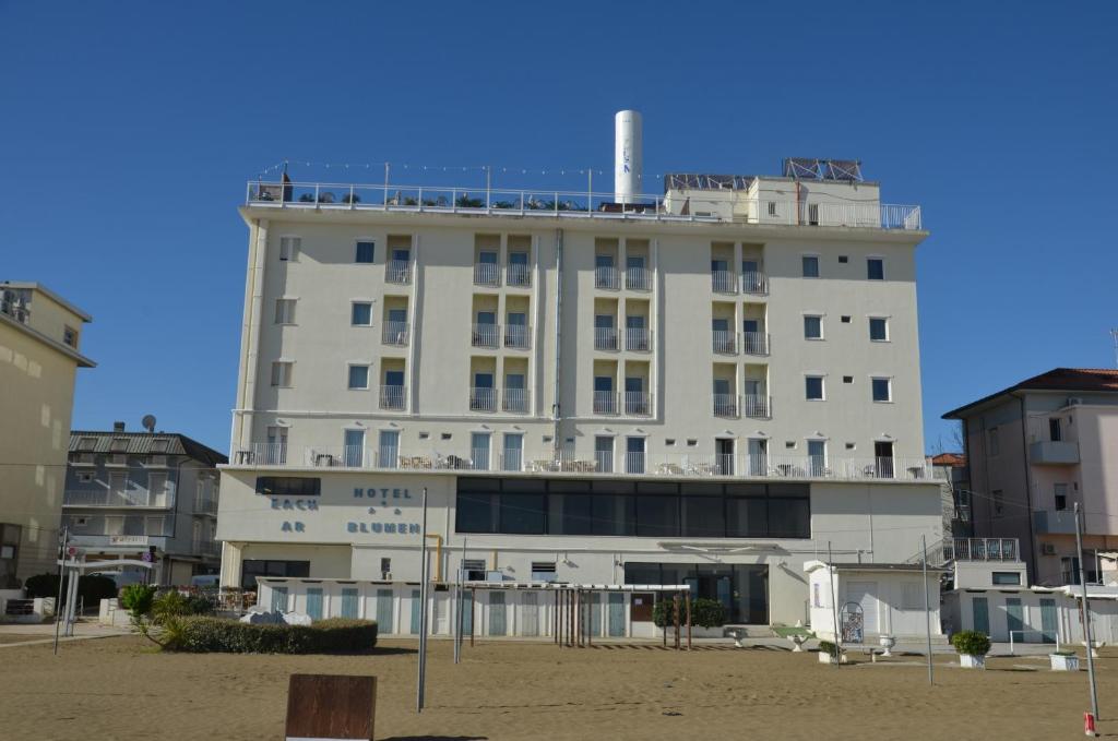 里米尼布鲁门酒店的海滩上一座白色的大建筑,有建筑