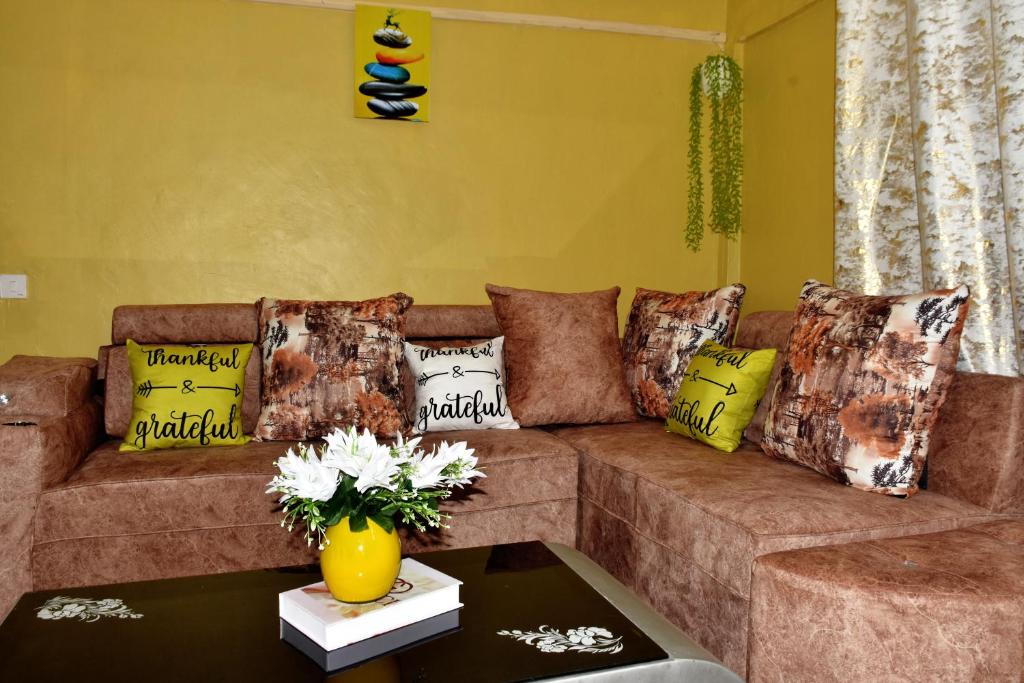 Kiambuone bedroom in oj town ruiru的客厅配有带色彩缤纷枕头的棕色沙发