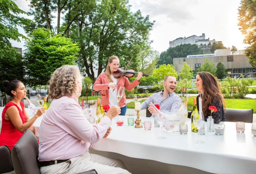 萨尔茨堡JUFA Hotel Salzburg的一群坐在桌边喝葡萄酒的人