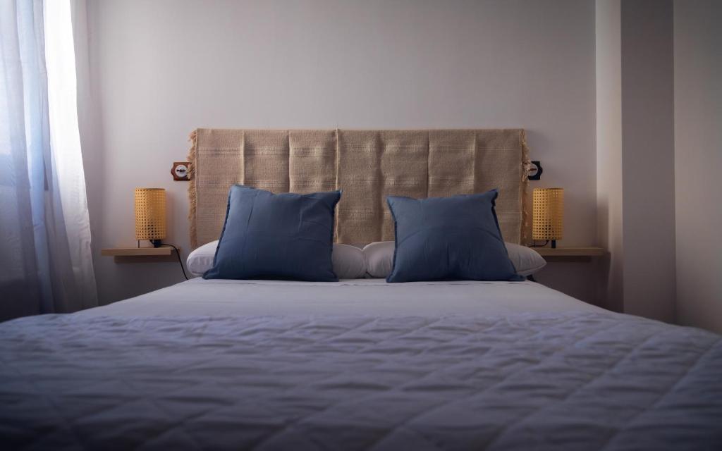 纳瓦尔卡内罗Hostal Corper Navalcarnero的一间卧室配有一张带蓝色枕头的床和两盏灯。
