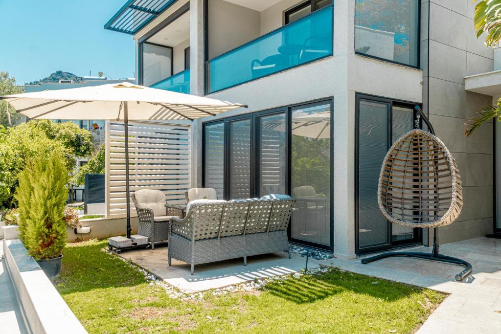 博德鲁姆Yalikavak Superior Duplex Villa的房屋设有带遮阳伞和椅子的庭院