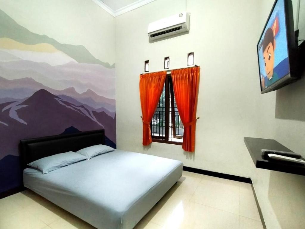 KalasanMamora Guest House的一间卧室配有床、电视和壁画