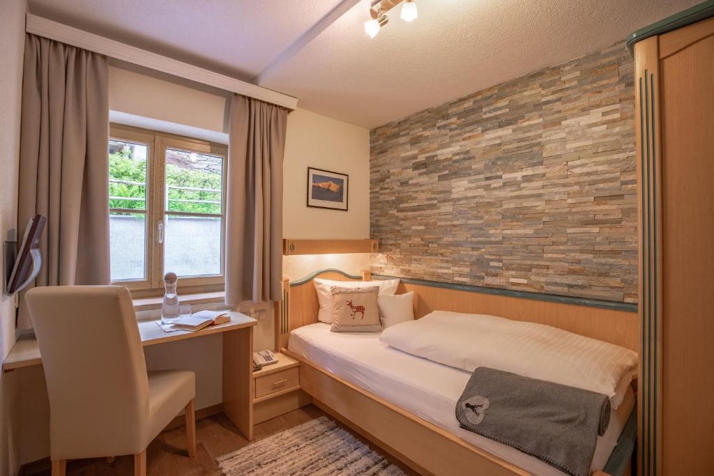 圣安东阿尔贝格Patteriol Apart-Hotel-Garni的一间卧室设有一张床和砖墙