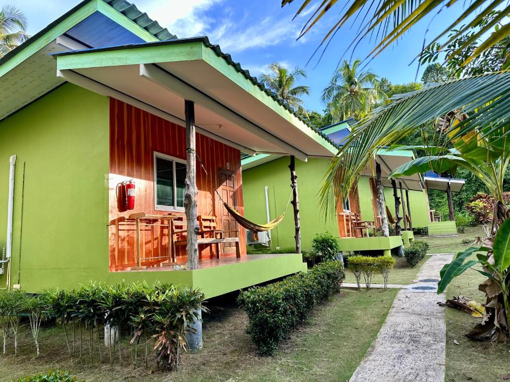 库德岛Suan Nai Kokut Resort的绿色和红色的房子,配有桌子和椅子