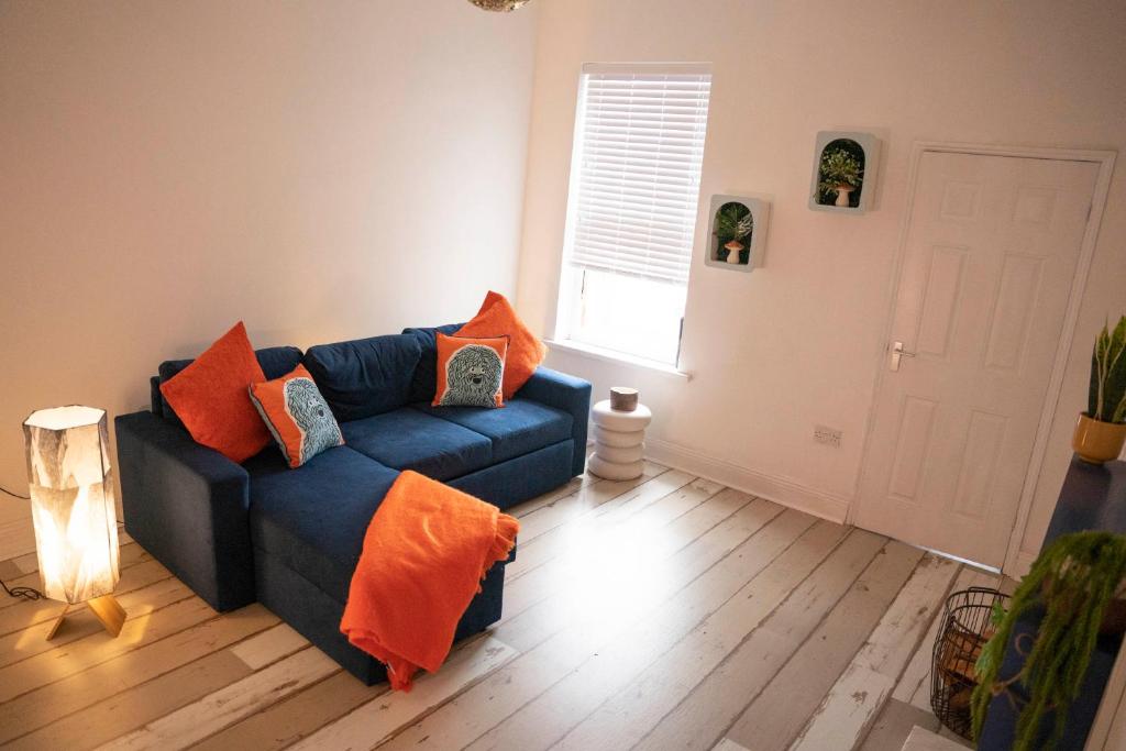 锡厄姆Sara’s Apartment的客厅配有蓝色长沙发及橙色枕头