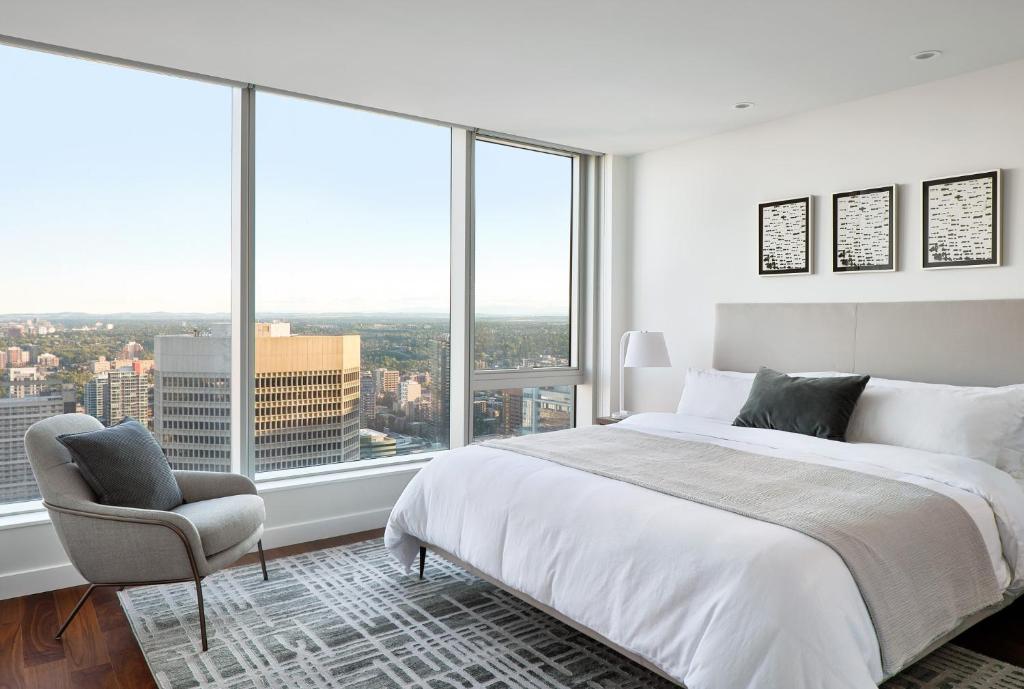 卡尔加里Award-Winning One-Bedroom Suite at Telus Sky的卧室配有床、椅子和大窗户