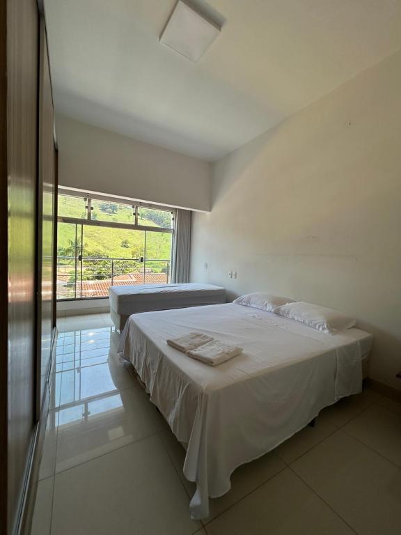 卡皮托利乌Suites Silva的白色的卧室设有床和大窗户