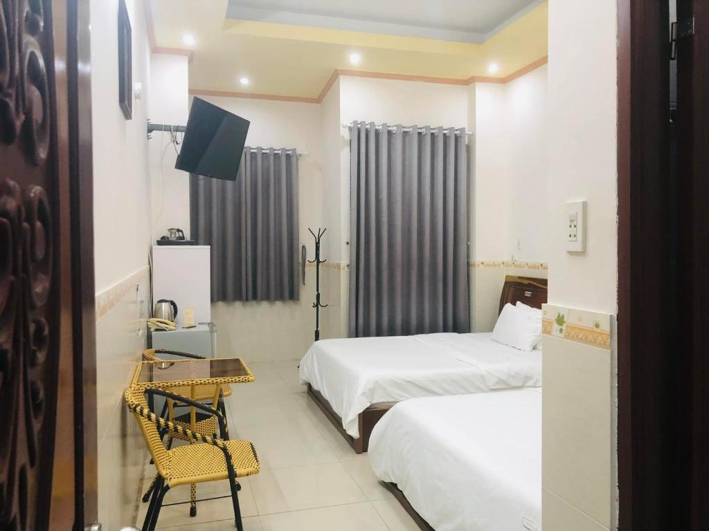 芹苴Huy Hoàng Motel - Cần Thơ的酒店客房设有两张床、一张桌子和一台电视。