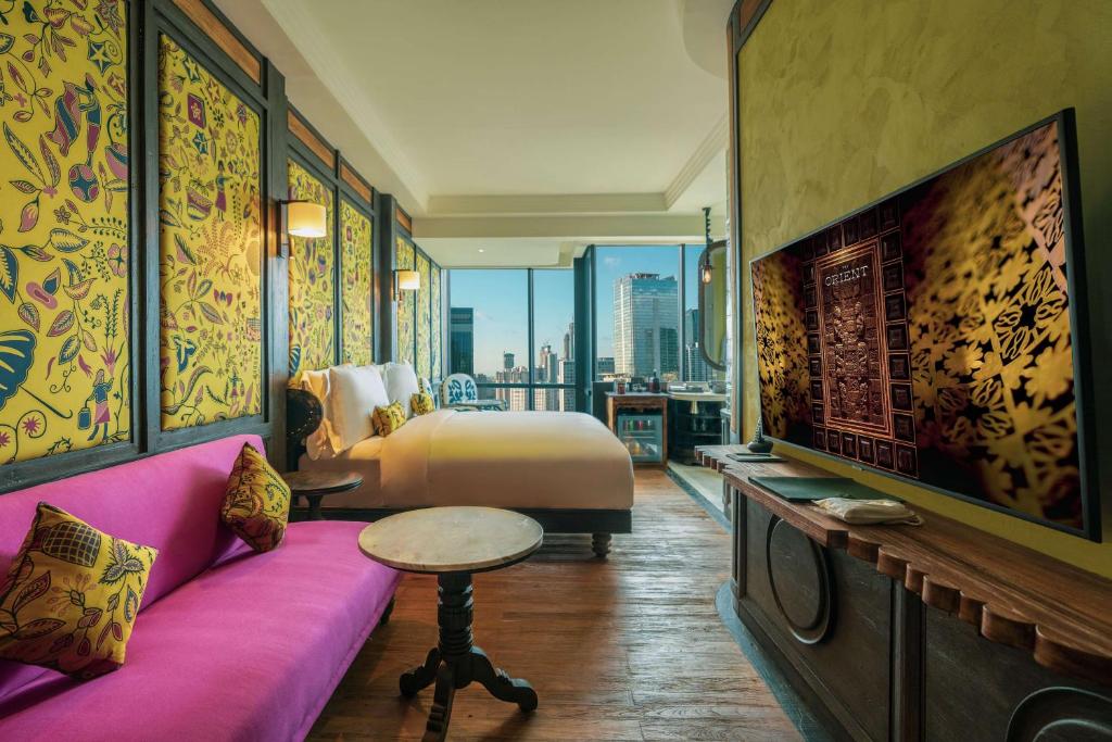 雅加达The Orient Jakarta, a Royal Hideaway Hotel的客房设有床、沙发和电视。