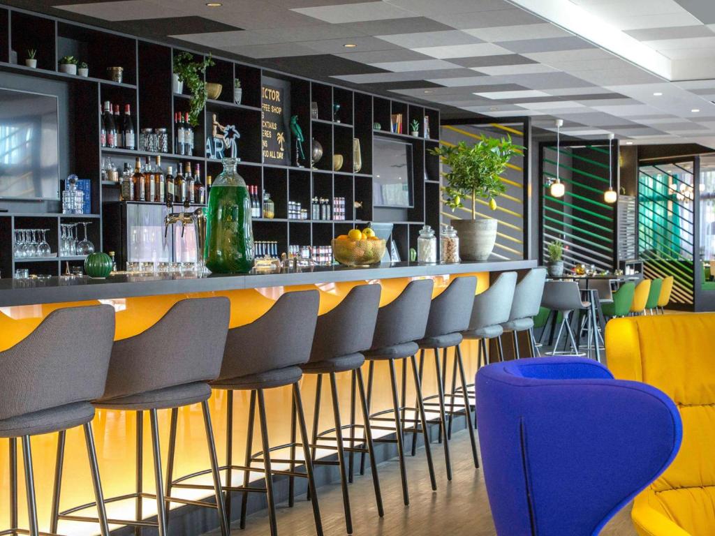 耶尔耶尔中心蔚蓝海岸美居酒店的餐厅内酒吧设有黄色和蓝色椅子