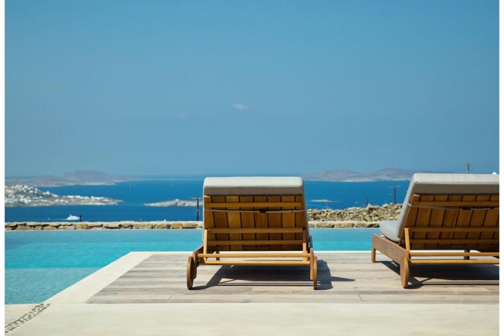 DexamenesSuper Luxury Mykonos Villa - Villa La Isla Bonita - Private Gym - Private Pool - 5 Bedrooms - Sea Views的游泳池畔的2把躺椅
