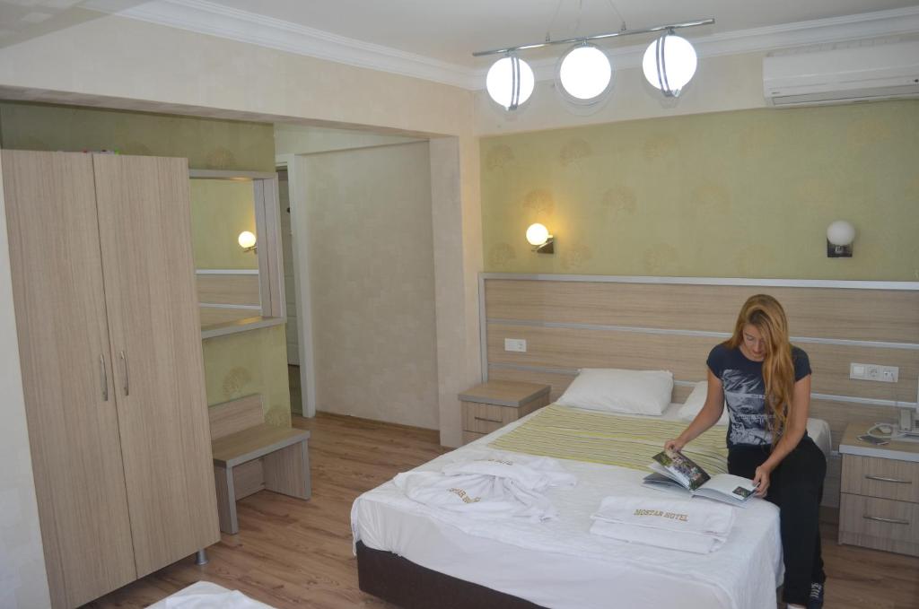 艾瓦勒克莫斯塔尔酒店的站在房间里床边的女人