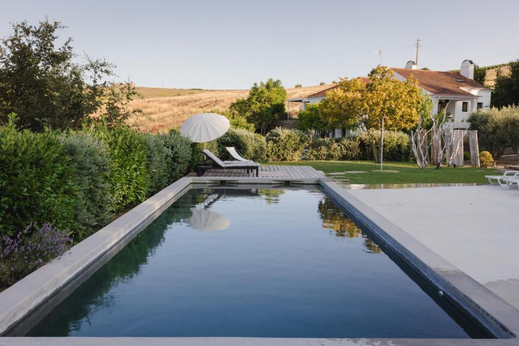Aldeia GavinhaCAMBEIROS - Guest House的庭院内的游泳池,配有桌椅