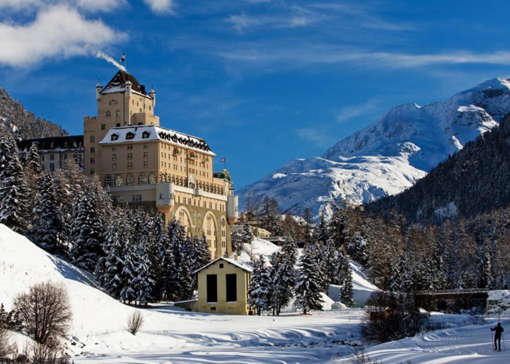 蓬特雷西纳Schloss Hotel & Spa Pontresina的雪中一座大建筑,有雪覆盖的群山