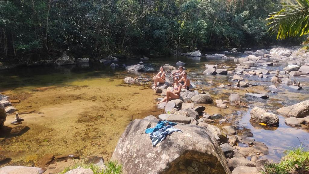 新弗里堡Sítio Kikiô - À Beira Rio em Lumiar的一群坐在河中岩石上的女人
