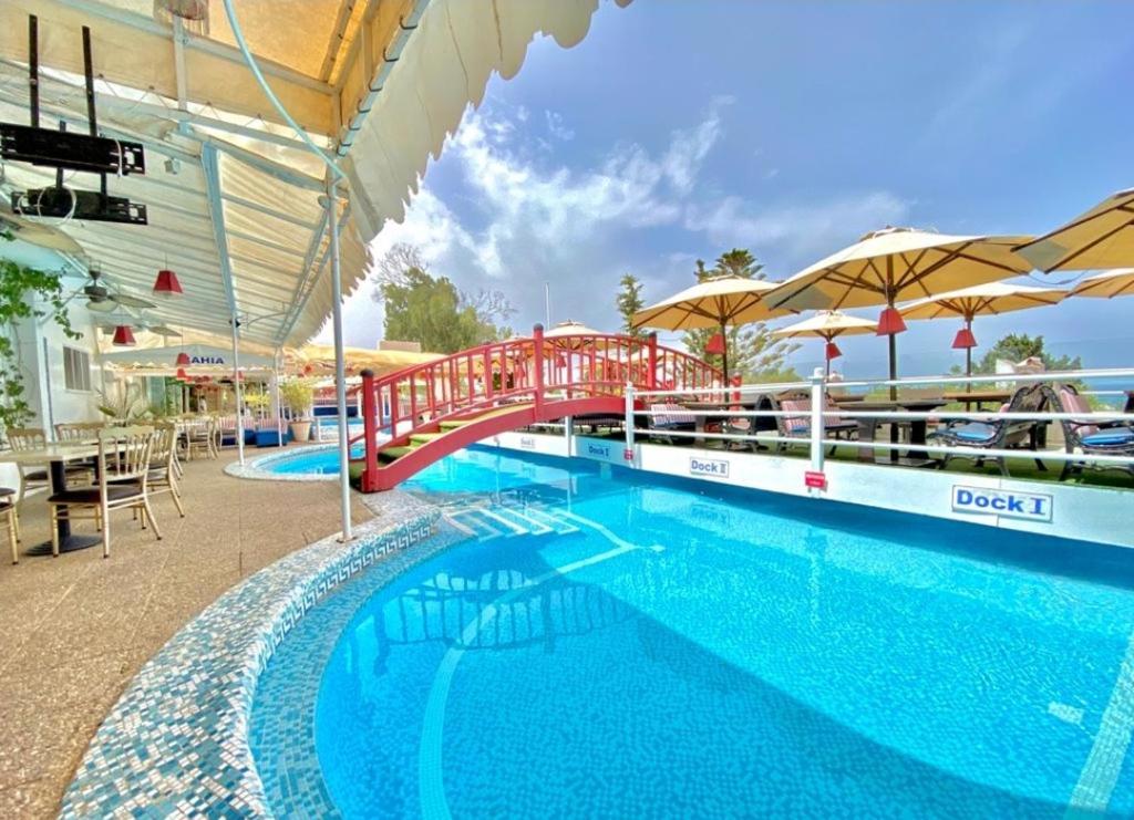 拉马萨Plaza Corniche的一个带红色桥梁和遮阳伞的大型游泳池
