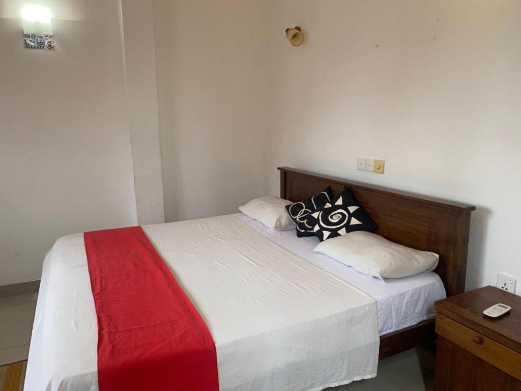 阿鲁特伽马JJ VILLA ALUTHGAMA的一间卧室配有一张带红白毯子的床