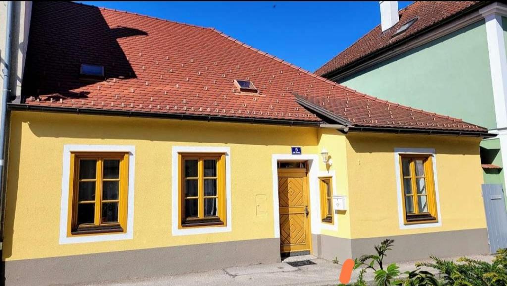 梅尔克Altstadthaus Marille mit Innenhofterrasse的红色屋顶的黄色小房子