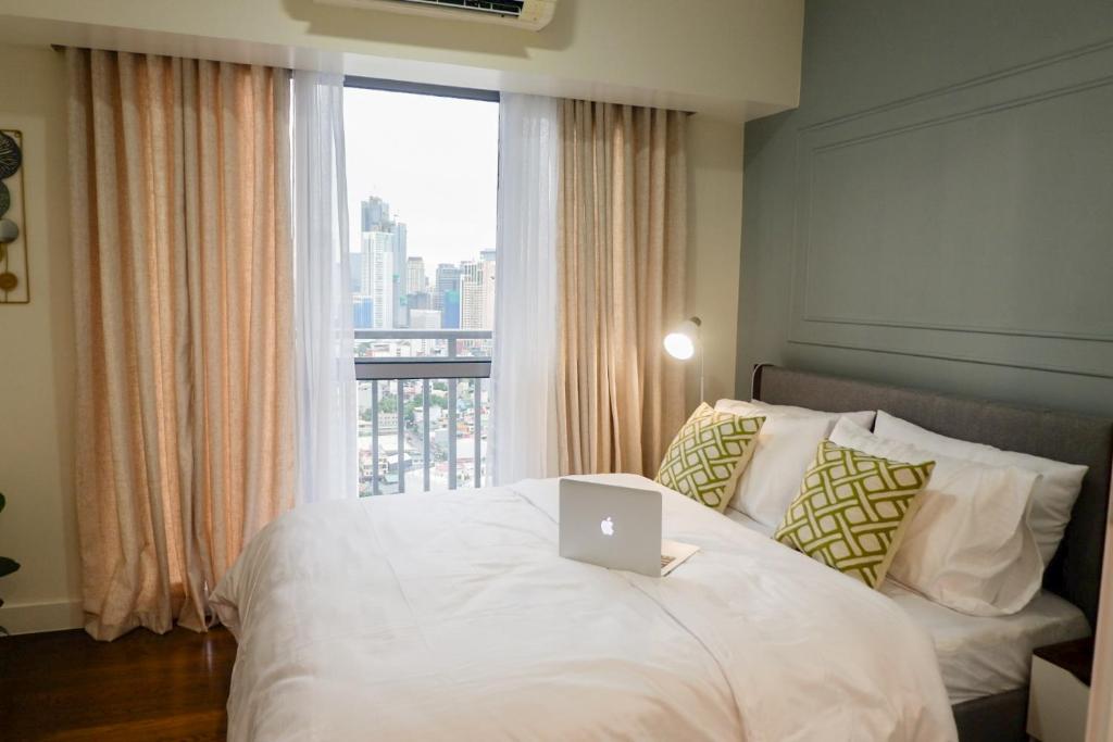 马尼拉Queen Suite with City View at Acqua Private Residences的一间卧室配有一张带笔记本电脑的床