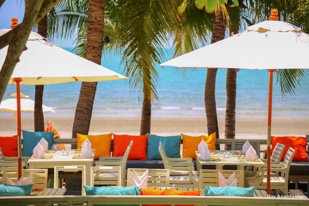 华欣Anantasila Beach Resort Hua Hin的一个带桌椅和遮阳伞的海滩