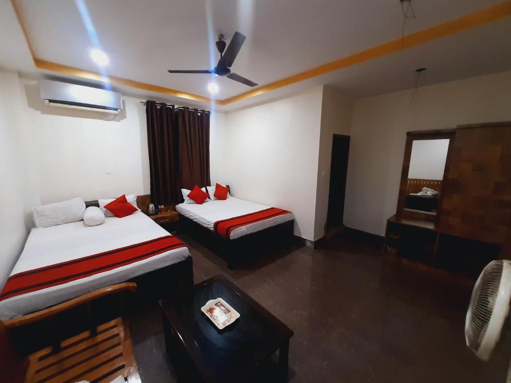 古瓦哈提Hotel Knight Inn Airport的酒店客房配有两张床和吊扇。