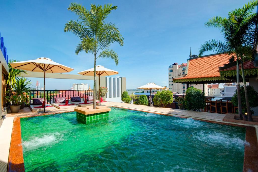 金边Apsor Palace Hotel的一座拥有绿色水源和棕榈树的游泳池