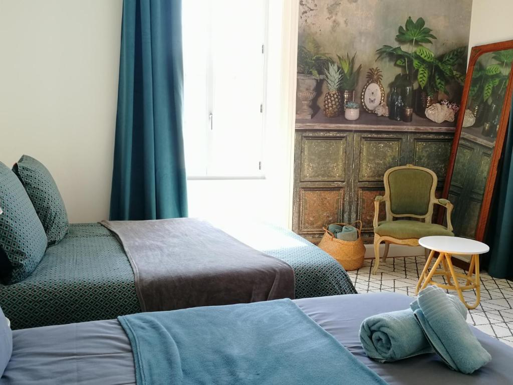 Saint-Amand-sur-Sèvrele gîte du fou logement 8 pers 13mn puy du fou的一间卧室设有两张床、一把椅子和一个窗户。