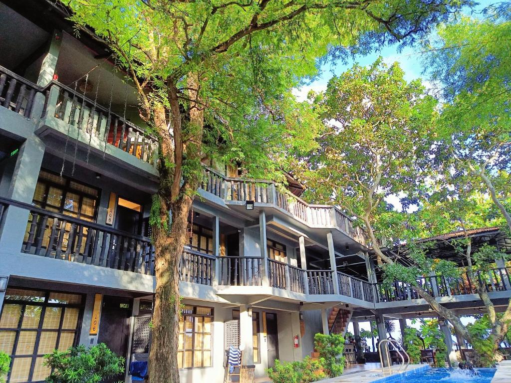 八打雁The Henry Resort Taramindu Laiya的公寓大楼前面有一棵树