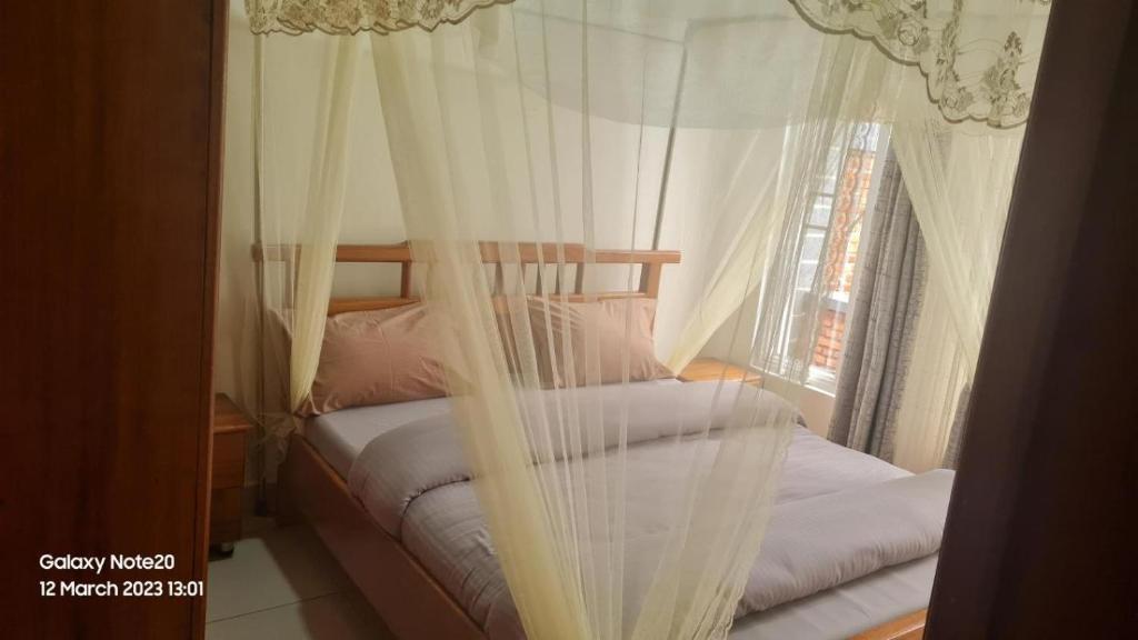 Room in Guest room - Charming Room in Kayove, Rwanda - Your Perfect Getaway的一间卧室配有两张床、白色窗帘和窗户