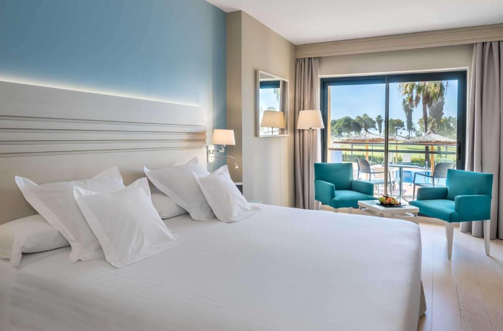 科斯塔巴伦娜巴瑟罗鲸鱼海岸高尔夫水疗酒店的卧室配有白色大床和蓝色椅子