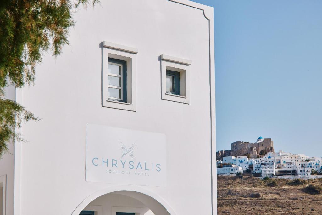 阿斯提帕莱亚镇Chrysalis Boutique - Adults Only的白色的建筑,上面有读书的标牌