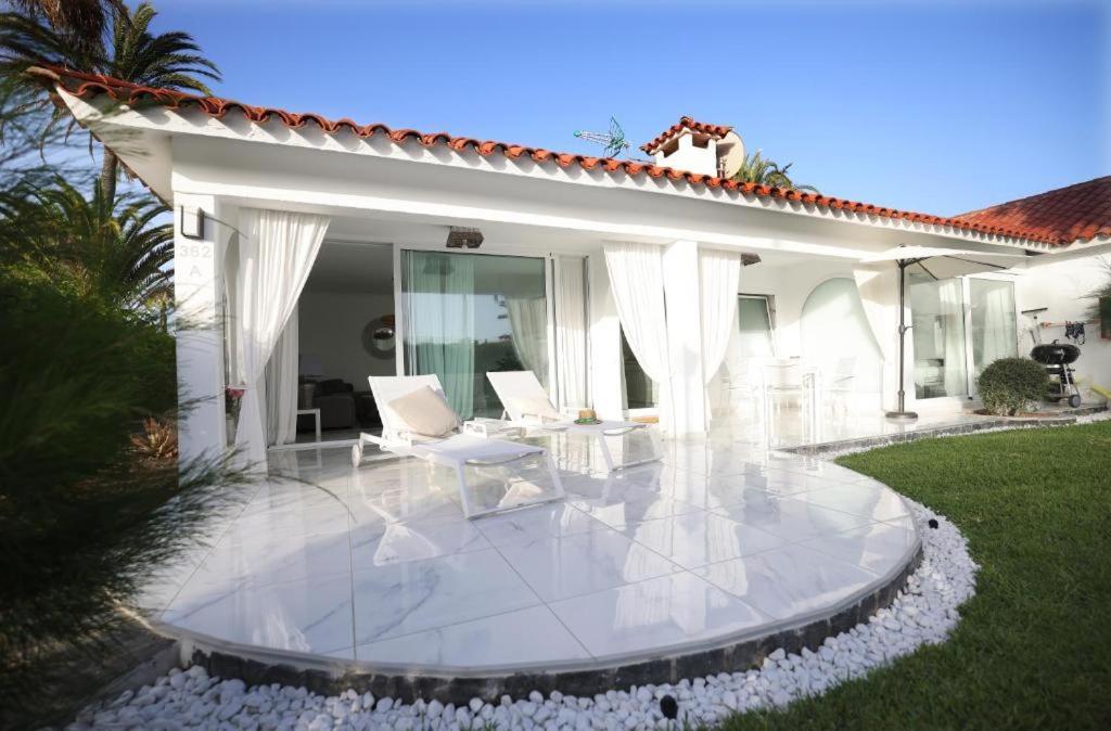 英格兰海滩Sun Club Playa del Ingles的一个带白色家具的庭院和一座房子