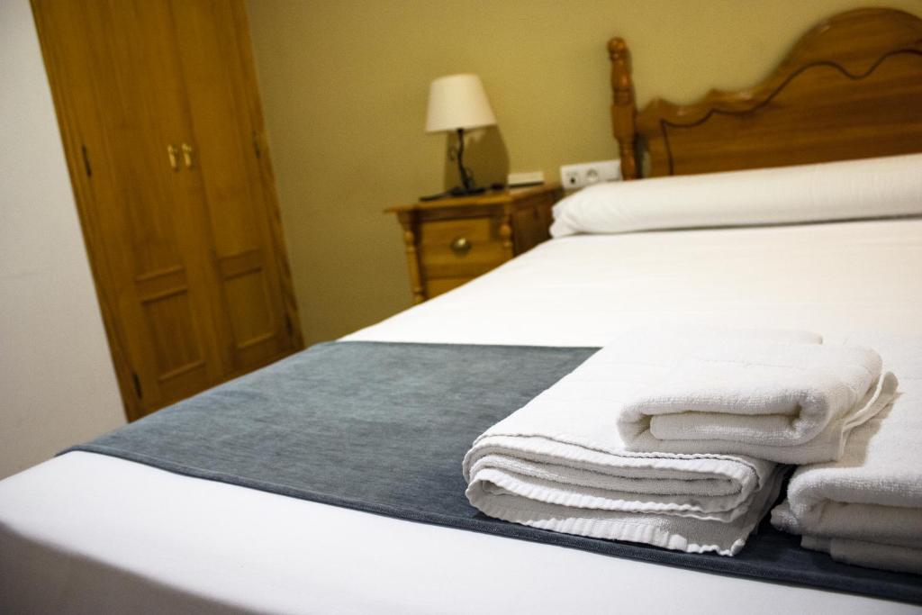 巴尔德佩尼亚斯Hostal Valdepeñas by Bossh Hotels的一间卧室配有一张带白色毛巾的床