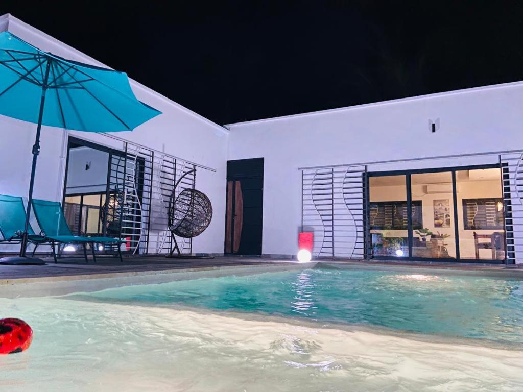 马哈赞加Villa sakinu的一个带蓝伞和桌子的游泳池