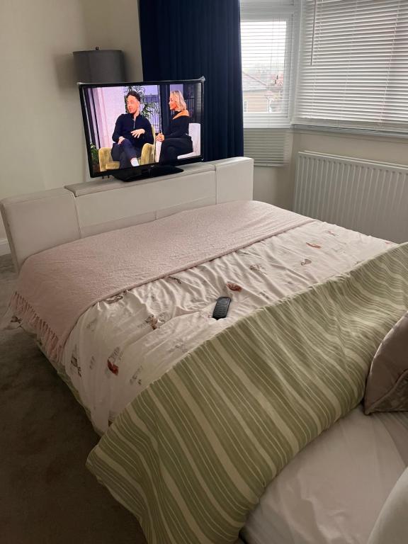 伦敦Home from Home Cosy B&B的卧室配有一张床铺,墙上配有电视