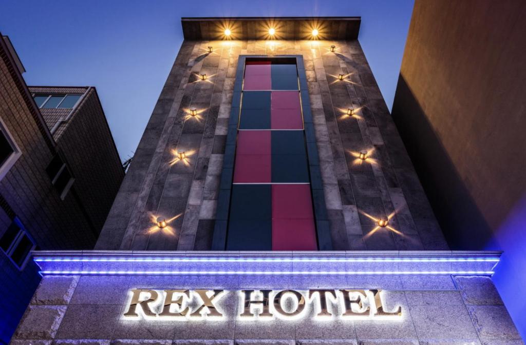 西归浦市Rex Hotel的一座建筑,上面有读雷克斯酒店的标志