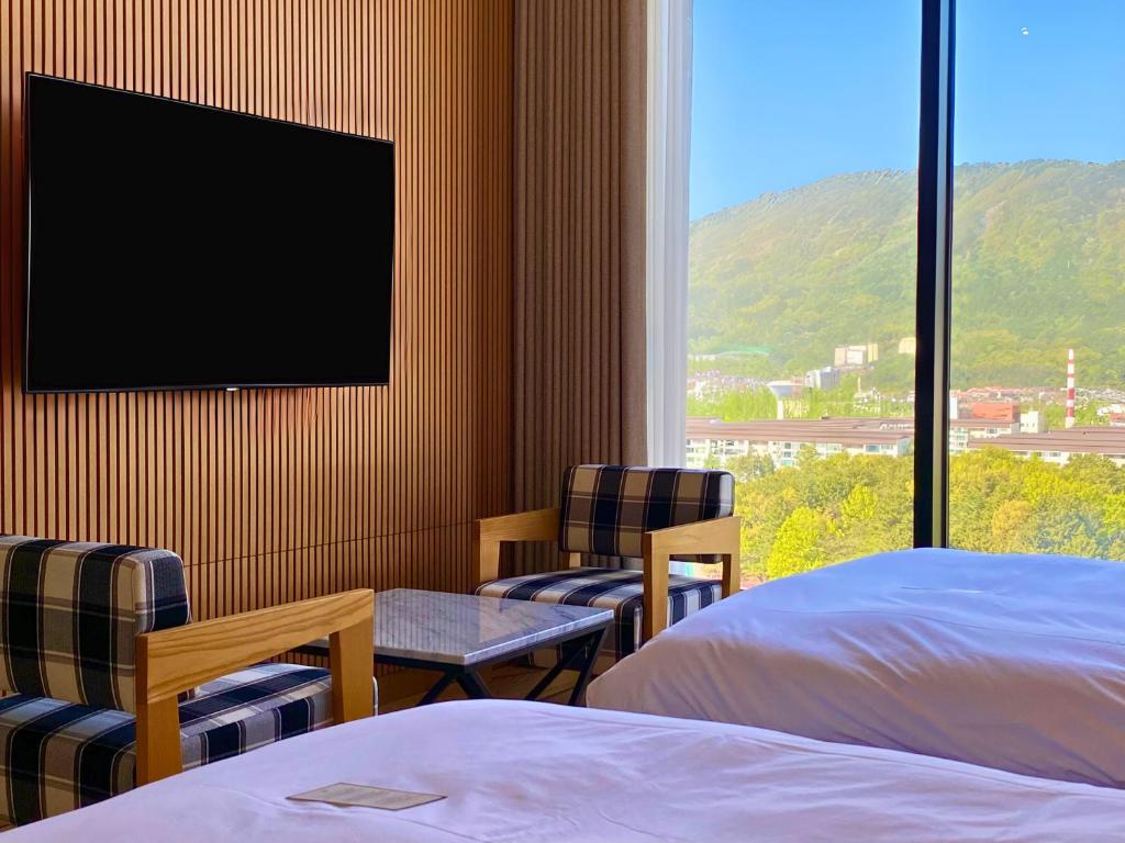 昌原市大道酒店的一间卧室配有一张床、两把椅子和电视