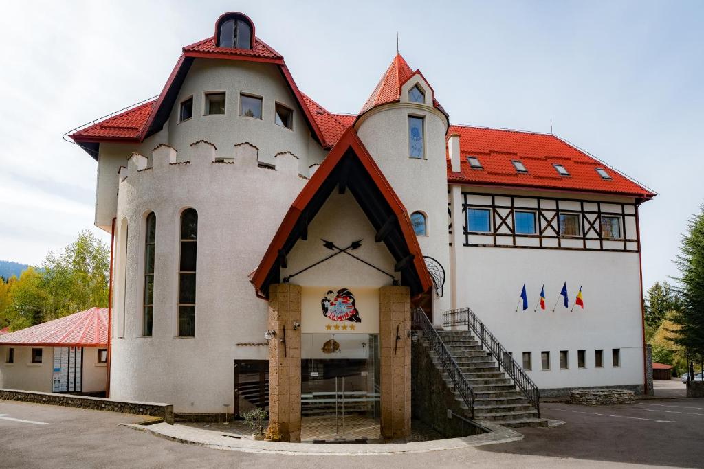 波亚纳布拉索夫德拉库拉之屋酒店的一座白色的大建筑,有红色的屋顶