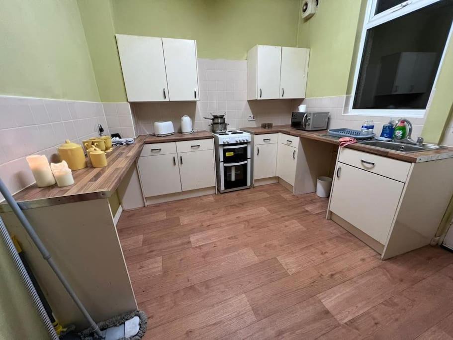 罗奇代尔Cosy 2 Bed House in Rochdale的厨房铺有木地板,配有白色橱柜。