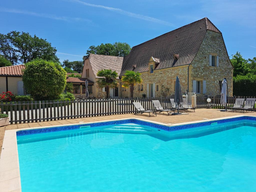 维特拉克La Barde Montfort, votre maison d'hôtes à 4 kms de Sarlat Dordogne的一座大蓝色游泳池,位于房子前