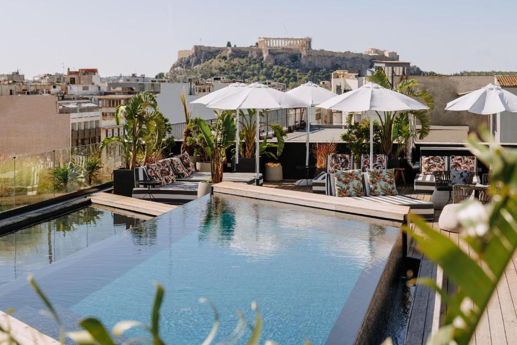 雅典Skylark, Aluma Hotels & Resorts的一座大楼内的游泳池,配有椅子和遮阳伞
