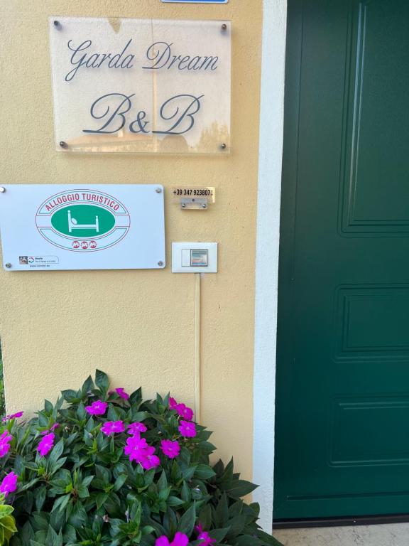 拉齐塞加尔达梦酒店的鲜花房子上的绿门和标志