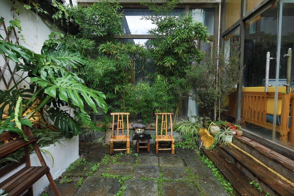 大理大理不羡山精品民宿的花园内种有植物,配有两把椅子和一张桌子