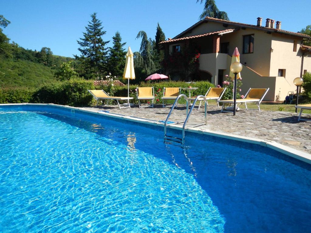 基安蒂格雷夫玻娜赛拉农庄别墅酒店的一个带椅子的蓝色游泳池以及一座房子