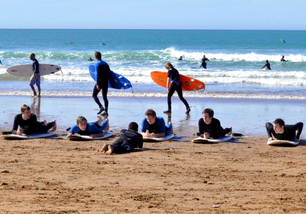 阿加迪尔Surf Lessons Experience with Hassi的一群人坐在海滩上,冲浪板