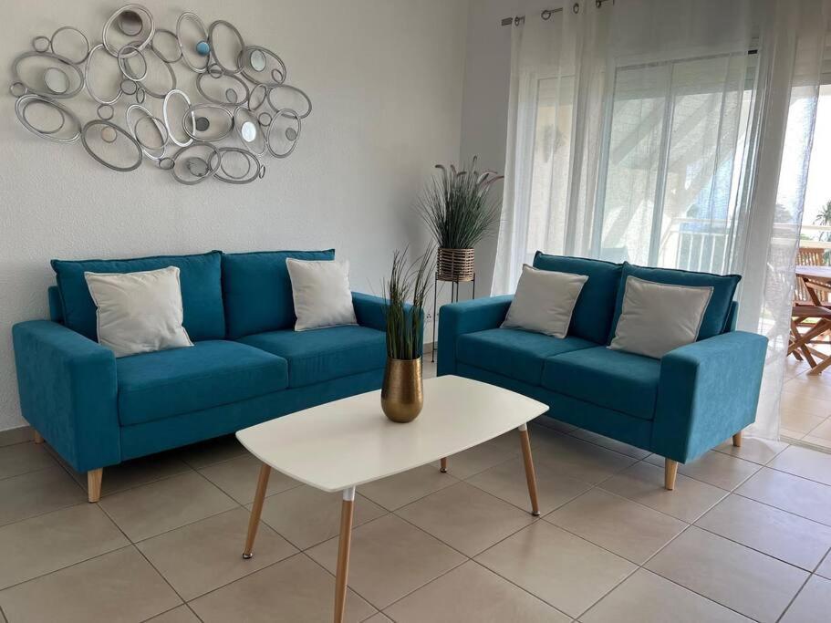 圣克洛德KANOA LODGE piscine et vue mer的客厅里设有一张蓝色的沙发和一张桌子