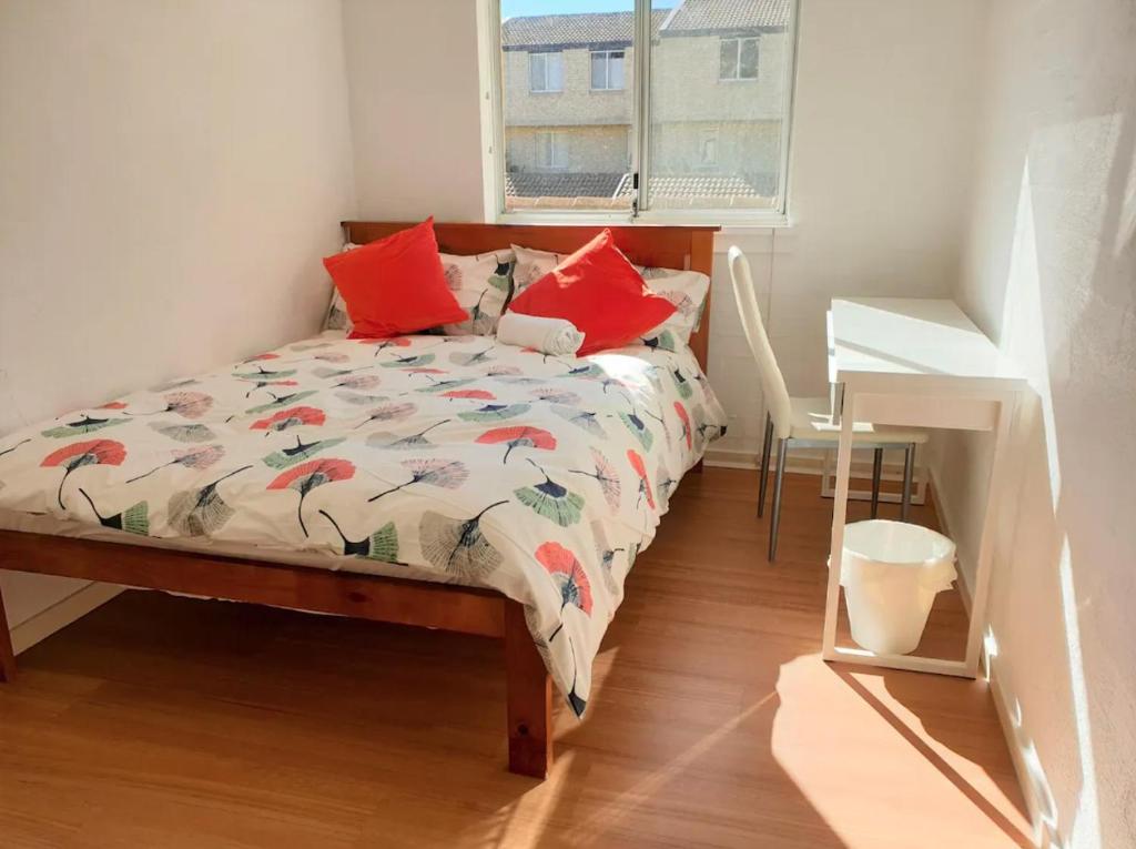 堪培拉Private Room in a 3-Bedroom Apartment-3的一间卧室配有一张带红色枕头的床和一扇窗户